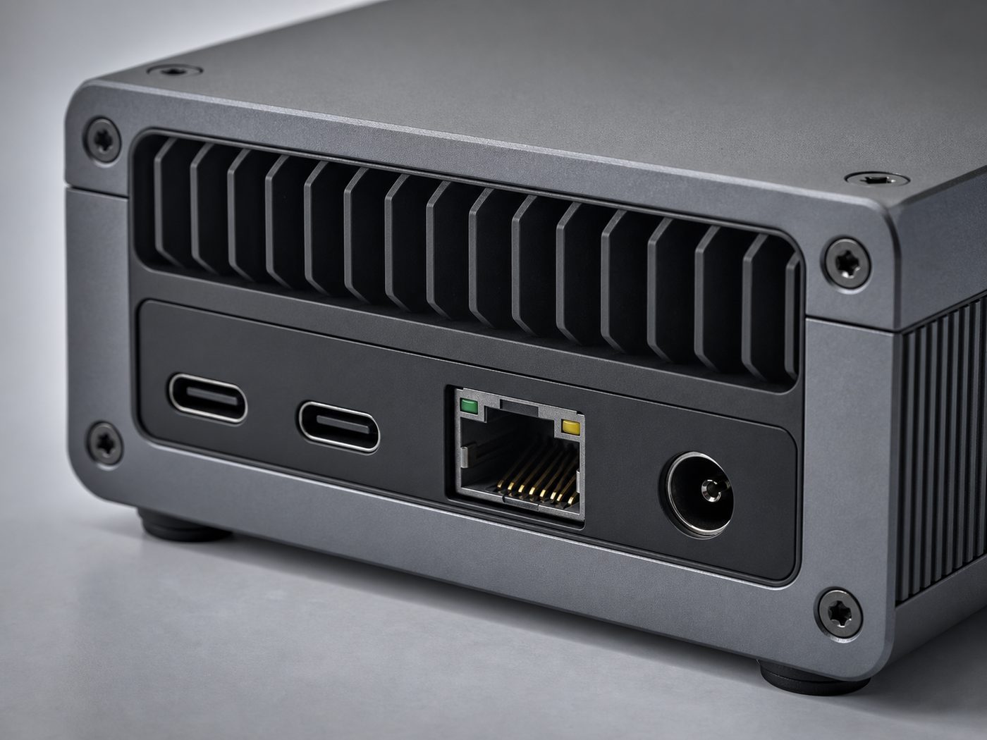 Closeup of gpuvera rear I/O: two USB-C ports, Ethernet, DC power, hex screws and a machined cooling grille — concept render, pre-production.