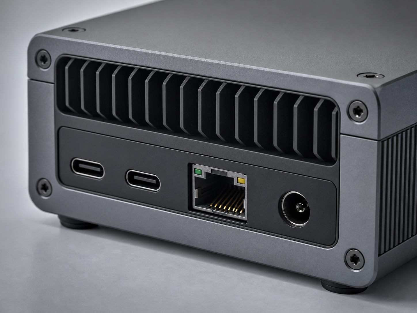 Closeup of gpuvera rear I/O: two USB-C ports, Ethernet, DC power, hex screws and a machined cooling grille — concept render, pre-production.